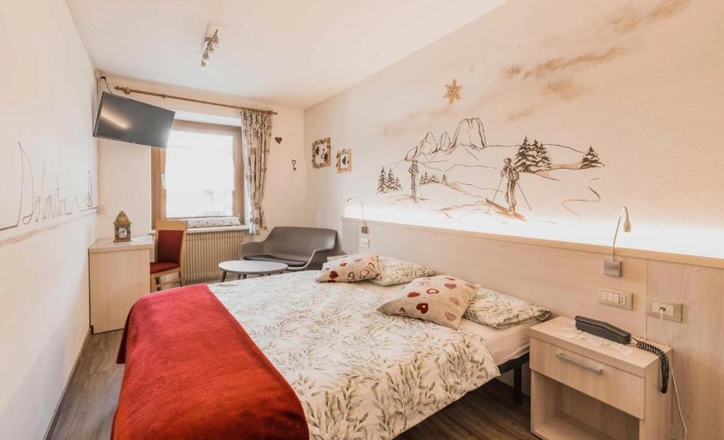 Mūsdienīgs viesnīcas numurs ar ērtu gultu, viesistabu un kalnu ainavas zīmējumu uz sienas, kas rada siltu un mājīgu atmosfēru.