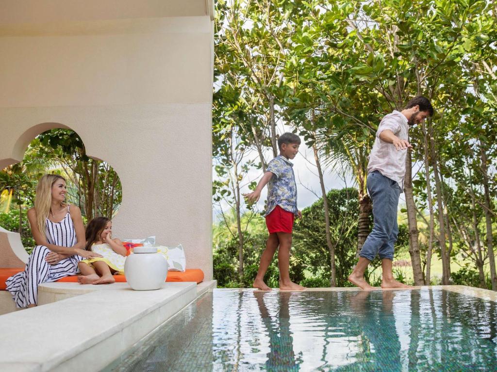 Ģimenes brīvdienu brīnums pie baseina, kur pieaugušie atpūšas, kamēr bērni rotaļājas un izbauda dabu.