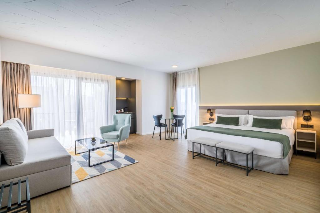 Mūsdienīgs viesnīcas numurs ar plašu gultu, ērtu dīvānu un galdu diviem, kas nodrošina komfortu un stilīgu atmosfēru. Lielie logi piepilda telpu ar gaismu un piedāvā piekļuvi ārējai terasei.