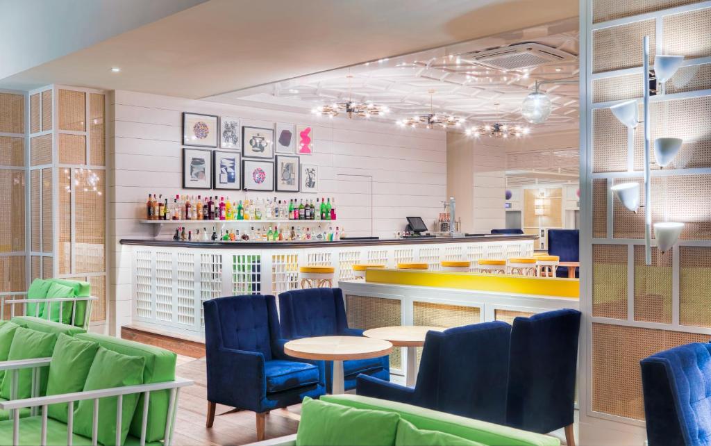 Mūsdienīgs bārs ar stilīgu interjeru, kurā ir krāsaini dīvāni un plaša alkoholisko dzērienu izvēle. Gaismas un mākslas elementi veido patīkamu atmosfēru.