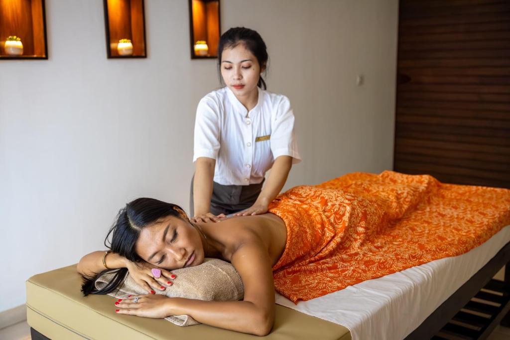 Sieviete saņem relaksējošu masāžu spa vidē, kur masiere ar uzmanību strādā pie viņas muguras. Apvienojot mierīgu atmosfēru un profesionālu apkalpošanu, šī aina attēlo relaksāciju un labsajūtu.