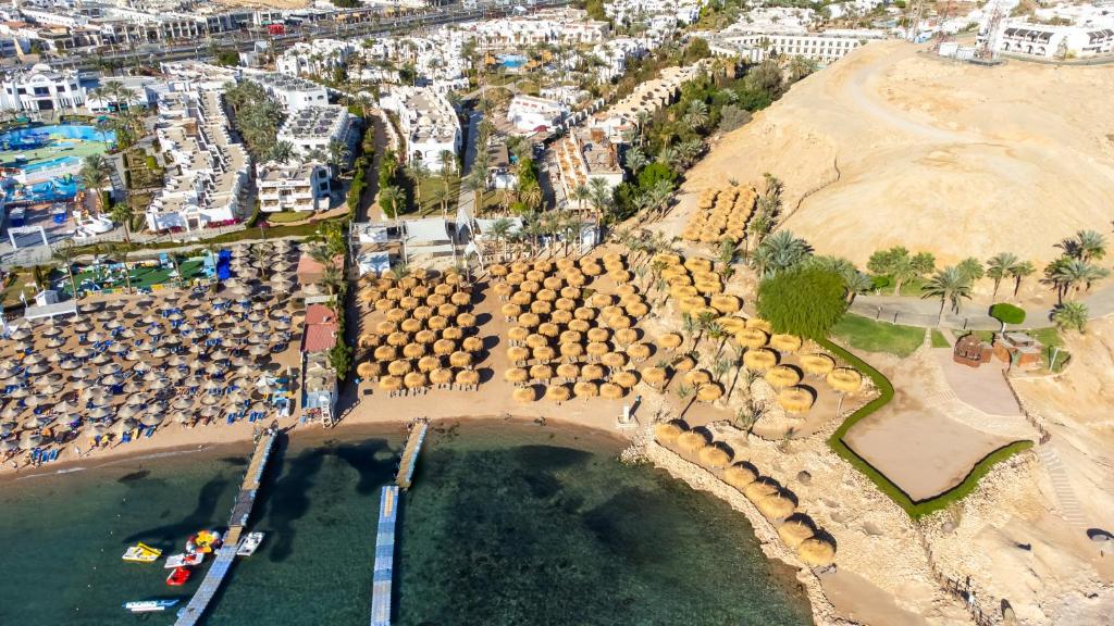 Pludmales skats ar saulessargiem un koka laivu piestātni, tālumā redzamas viesnīcas un zaļumi. Šī ainava piedāvā relaksācijas iespējas pie ūdens un skaistu apkārtni.