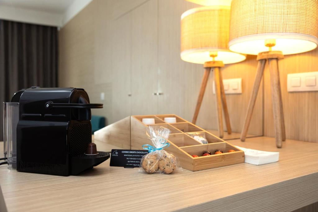 Mūsdienīga galda dizaina aina ar Nespresso kafijas automātu, koka uzkodu trauku un gaismas lampām. Ideāla atmosfēra relaksācijai un baudīšanai.