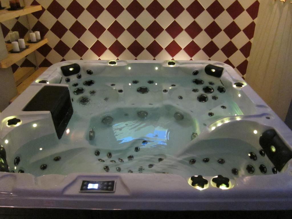 Lielā, modernā burbuļvannā ar dažādām gaismiņām un akmeņiem ūdenī, kas atrodas telpā ar stilīgu flīžu sienu.