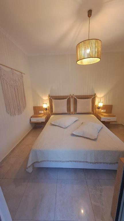 Mūsdienīgs guļamistabas interjers ar divguļamo gultu, koka naktsgaldiņiem un siltu apgaismojumu. Gultas veļa ir gaiša, un telpā ir mākslinieciskas detaļas, piemēram, makramē sienas dekors.