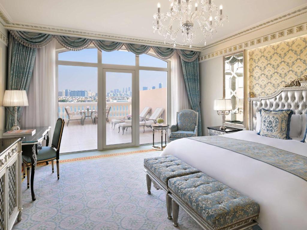 Luksusīga viesnīcas numura interjers ar elegantām mēbelēm, izsmalcinātiem audumiem un skatu uz pilsētu caur plašiem logiem. Bilancē ir gultas ar krāšņu apdari un gaismas ķermenis, kas piešķir telpai eleganci.