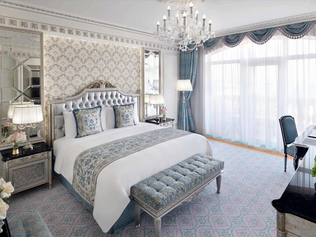 Eleganta viesnīcas numurs ar greznām mēbelēm, izsmalcinātu gultu un gaismas lustru. Logi ar caurspīdīgiem aizkariem ļauj ieplūst dabīgajai gaismai.