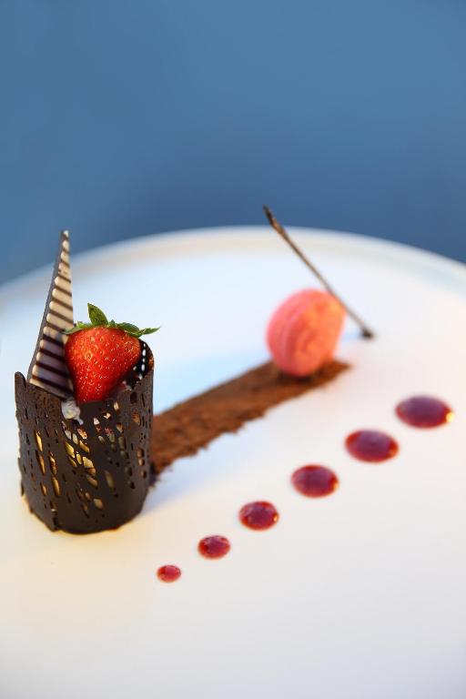 Elegantais deserts ar šokolādes dekoru, zemeņu un makaronu, kas papildināts ar ogu mērci.