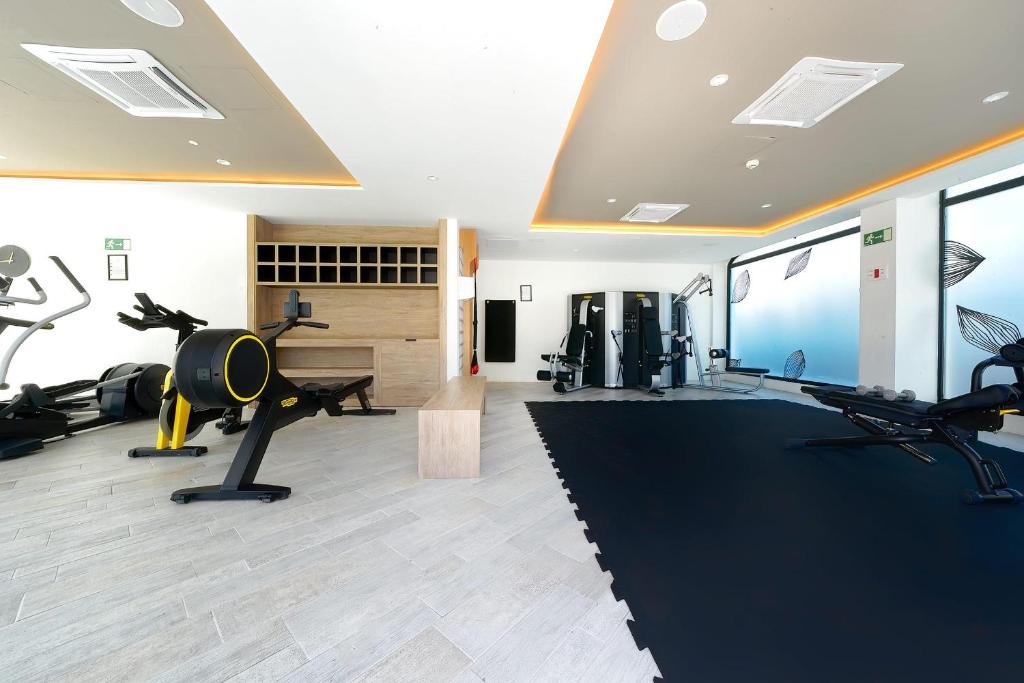 Mūsdienīga sporta zāle ar dažādām treniņu ierīcēm un plašu, gaišu interjeru. Telpā ir redzams melns paklājs, kā arī glīti iekārtotas uzglabāšanas vietas.