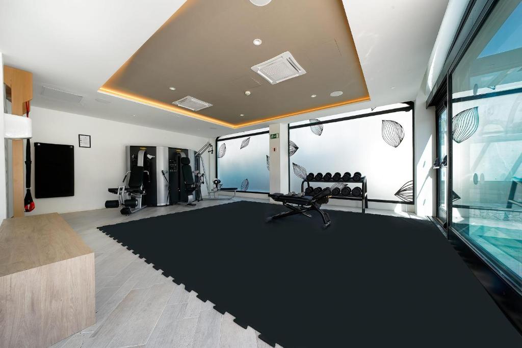 Mūsdienīga sporta zāle ar modernām trenažieru iekārtām, svaru stieņiem un plašiem logiem, kas nodrošina dabīgu apgaismojumu. Telpa ir aprīkota ar elastīgu grīdas segumu un dekoratīvām sienām.