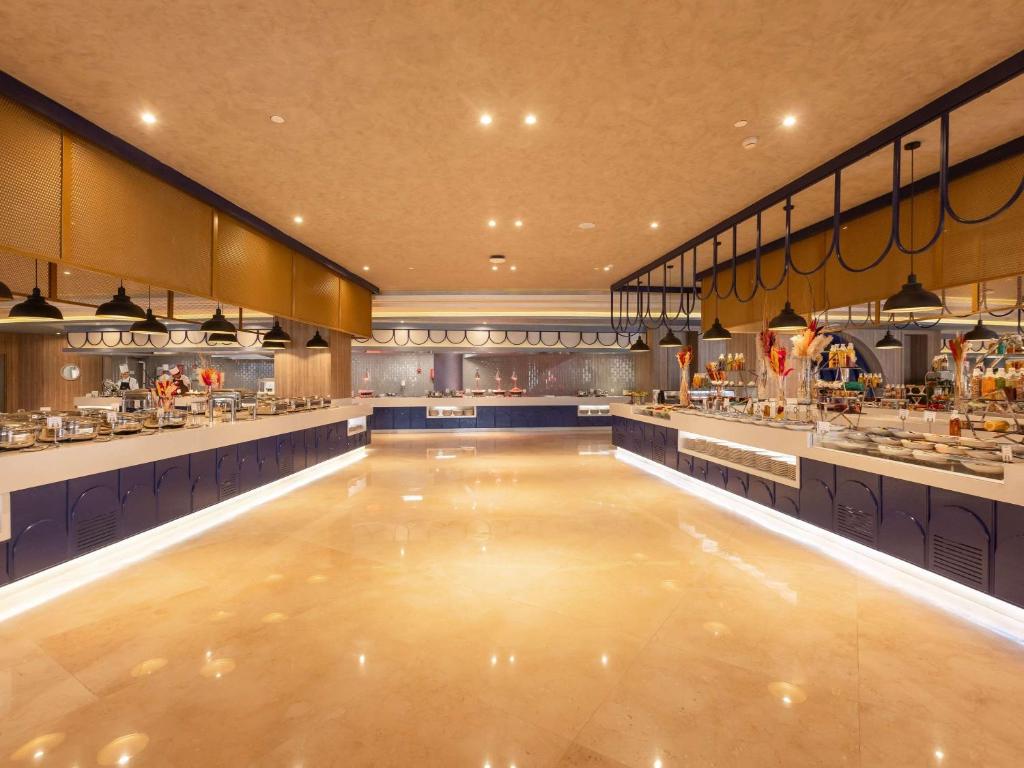 Mūsdienīgs un plašs bufete restorāns ar elegantu interjeru, kas piedāvā dažādas ēdienu izvēles. Apgaismojums un dizains rada siltu un aicinošu atmosfēru.