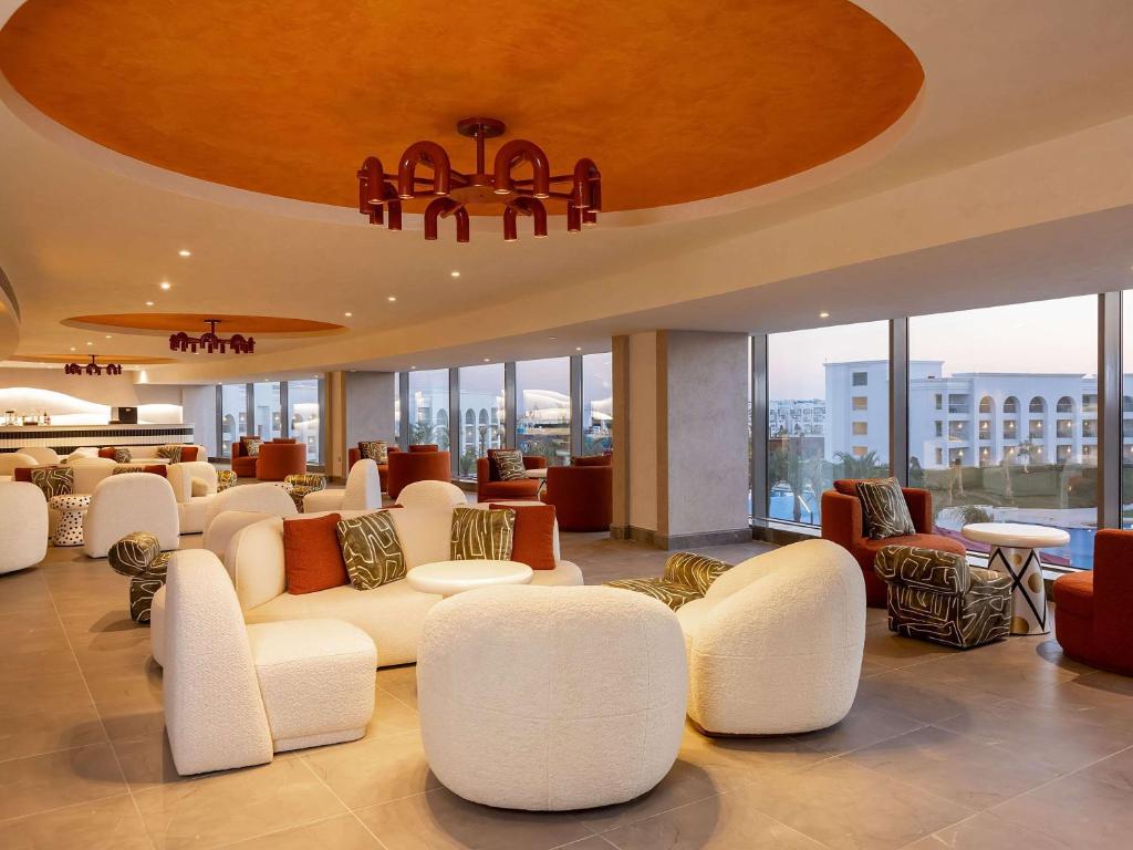 Mūsdienīgs viesnīcas interjers ar komfortablām sēdvietām un elegantām griestu lampām, kas rada relaksējošu atmosfēru. Lielie logi piedāvā skatu uz ārpusi un dabīgu apgaismojumu.