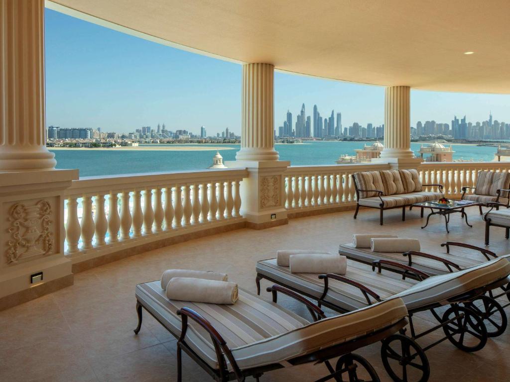 Grezna terase ar skatu uz Dubaijas pilsētas ainavu un jūru, kurā ir sauļošanās krēsli un dīvāni.