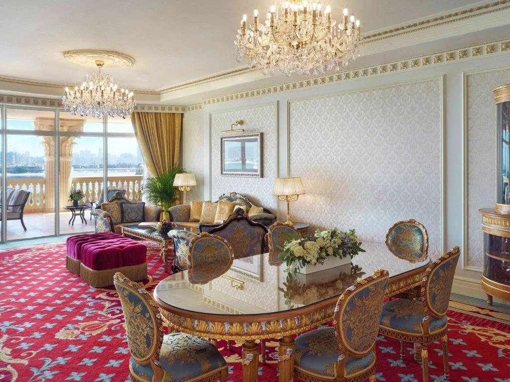 Greznas viesnīcas numura iekārtojums ar elegantu mēbeļu komplektu, lustru un panorāmas logiem, kas sniedz skatu uz pilsētu. Izteiksmīgas krāsas un grezni dekori rada luksusa atmosfēru.