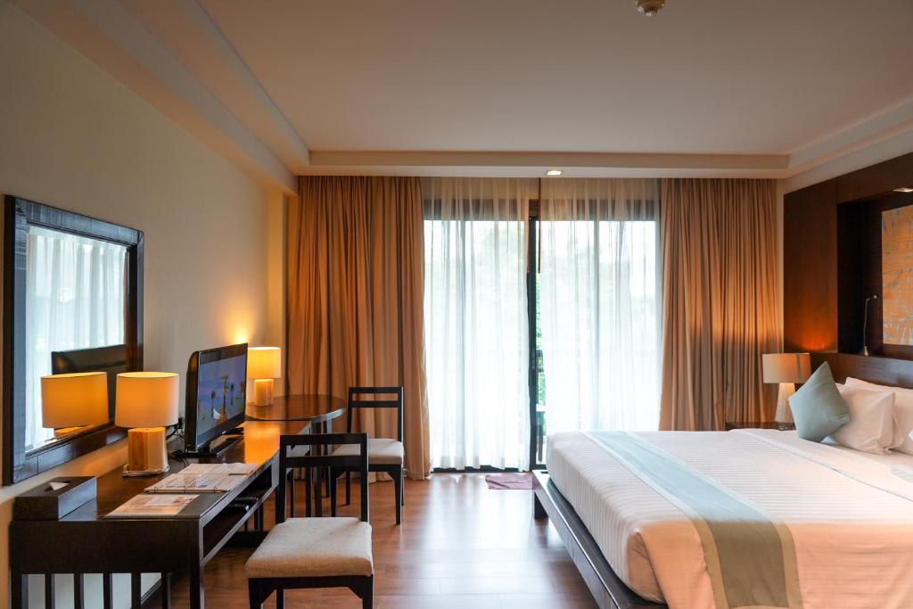 Mūsdienīga viesnīcas numura interjers ar plašu gultu, rakstāmgaldu un televizoru, kas atrodas blakus lieliem logiem ar aizkariem. Gaismas un krāsu kombinācija rada siltu un mājīgu atmosfēru.