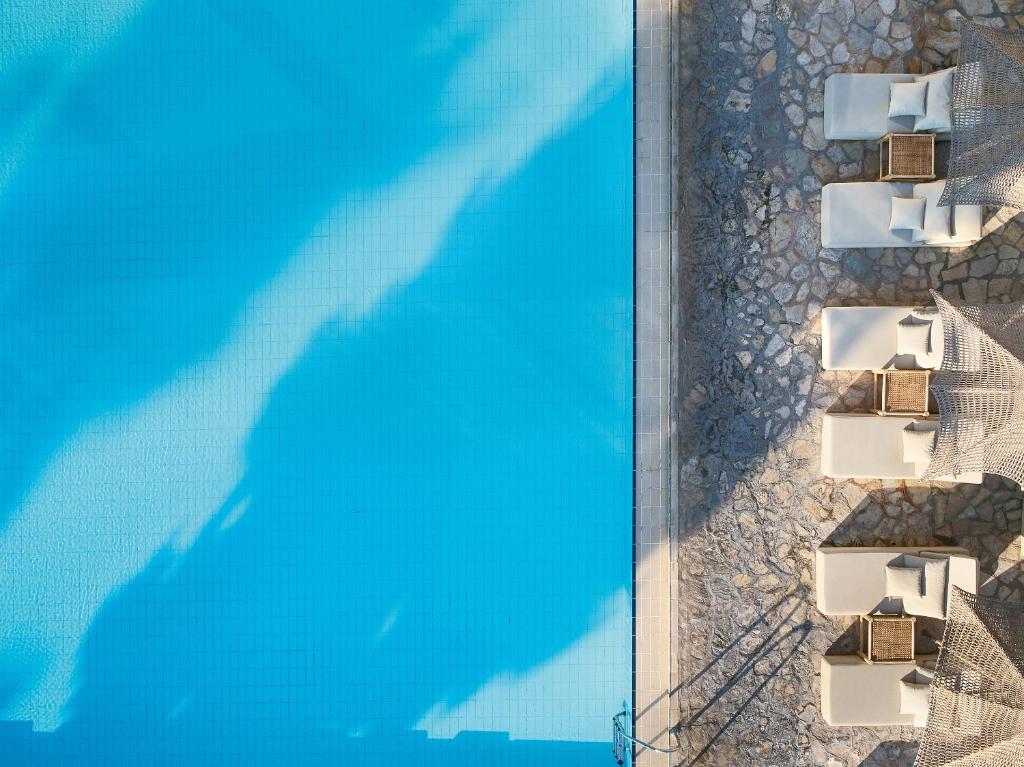 Peldbaseins ar skaidru zilu ūdeni un atpūtas krēsliem blakus, veidojot relaksējošu atmosfēru. Ideāla vieta atpūtai un saulē.