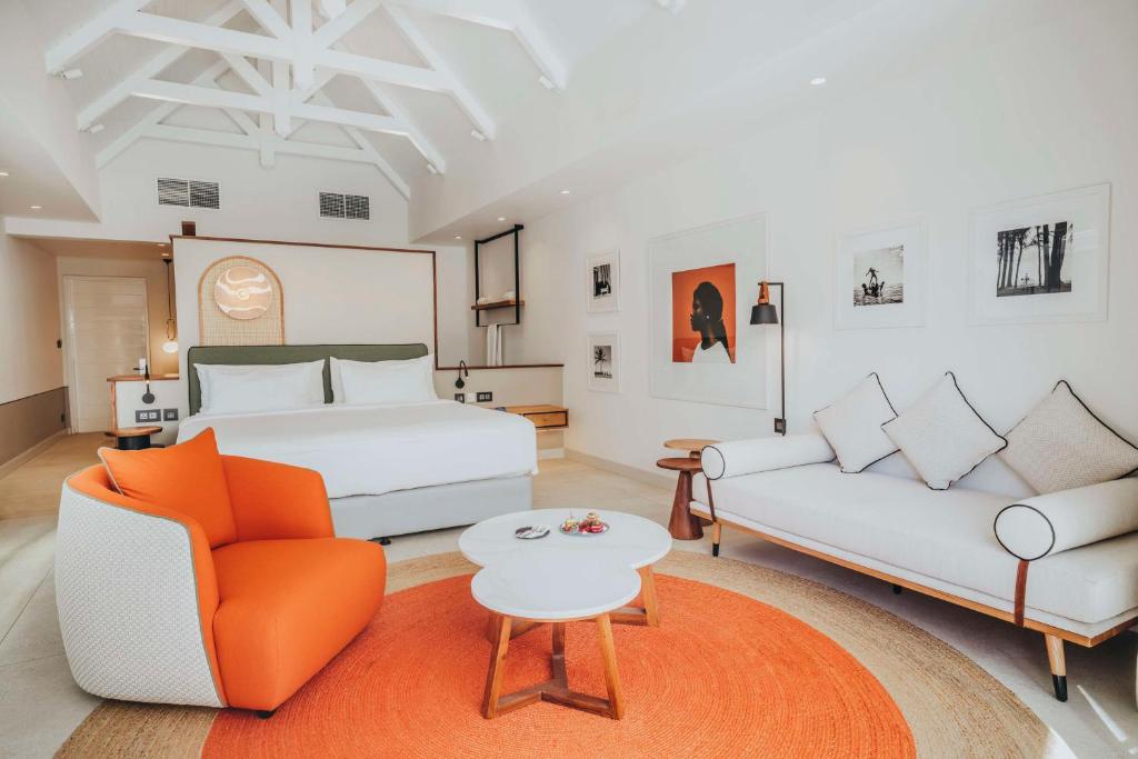 Mūsdienīgs viesnīcas numurs ar gultu, sēdvietām un mākslas darbiem uz sienām, radot relaksējošu atmosfēru. Interjers ir gaišs un elegants, ar akcentiem no oranžas krāsas.