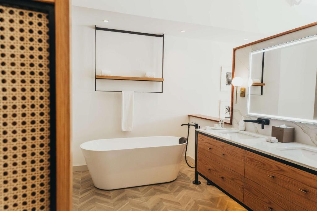 Mūsdienīga vannas istaba ar brīvo stūra vannu, elegantu koka skapīti un modernām apgaismojuma ierīcēm. Interjers apvieno minimālisma un komforta elementus.