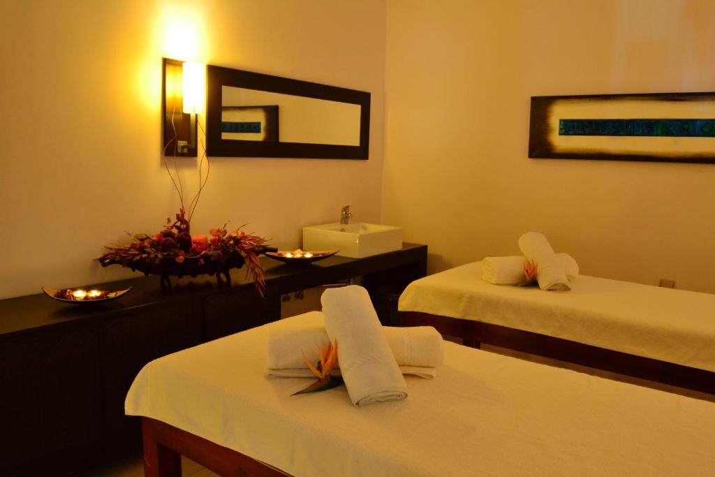 Spa telpa ar divām masāžas galdiem, apgaismota ar siltu gaismu, dekorēta ar ziediem un svecēm. Eleganta un relaksējoša atmosfēra.