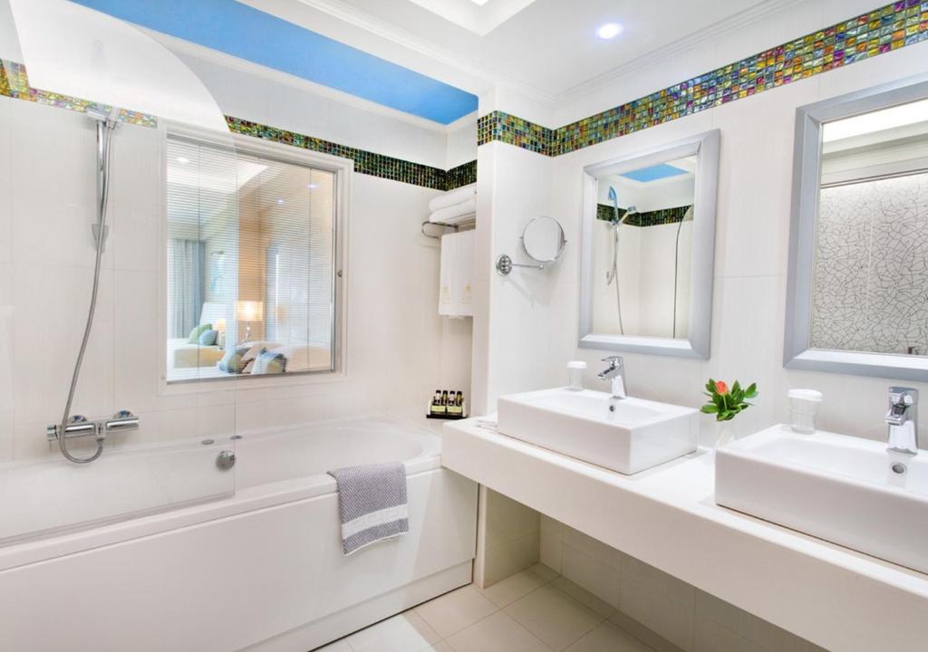 Moderns vannas istabas iekārtojums ar dubultajiem izlietnēm un vannu. Gaismas un krāsainu flīžu akcenti piešķir telpai svaigumu.