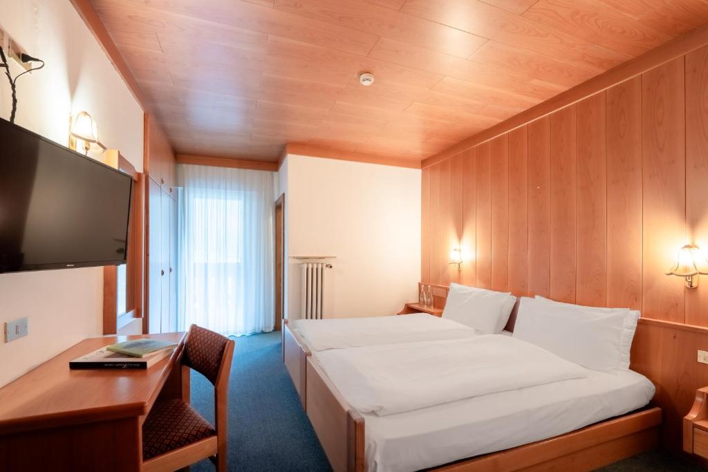 Mūsdienīga viesnīcas istaba ar divām gultām, koka apdari un televizoru, kas nodrošina komfortablu atpūtu. Logi ar caurspīdīgām aizkarām ļauj ieplūst dabiskai gaismai.