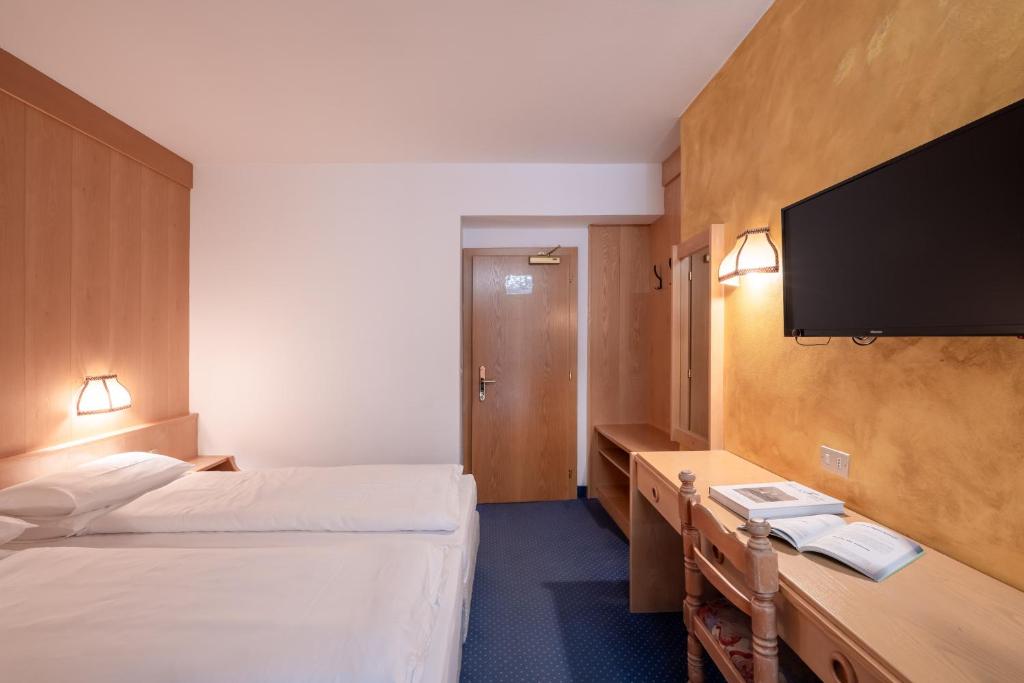 Mūsdienīgs viesnīcas numurs ar divām gultām, koka mēbelēm un televizoru pie sienas. Telpā ir arī galda vieta un apgaismojums.