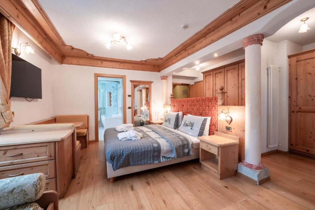 Mūsdienīgs guļamistabas interjers ar koka apdari, ērtiem gultasveļas izstrādājumiem un piekļuvi vannas istabai. Istaba aprīkota ar televizoru un mēbelēm, kas rada mājīgu atmosfēru.