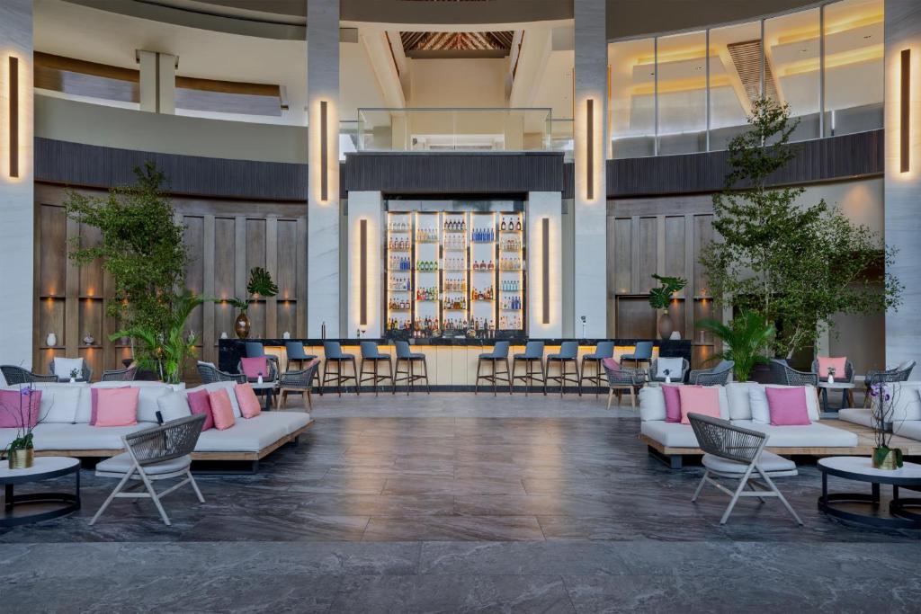 Mūsdienīga viesnīcas recepcija ar elegantu bāru, kas dekorēts ar zaļumiem un spilgtām krāsām. Ērti dīvāni un krēsli rada relaksējošu atmosfēru.