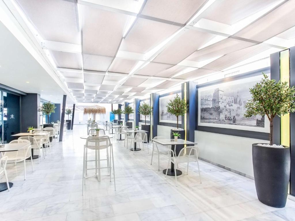 Mūsdienīgs restorāns ar gaišu, plašu interjeru, kurā ir eleganti galdi un krēsli, kā arī dekoratīvi augi. Sienas rotā melnbaltas gleznas, radot patīkamu atmosfēru.