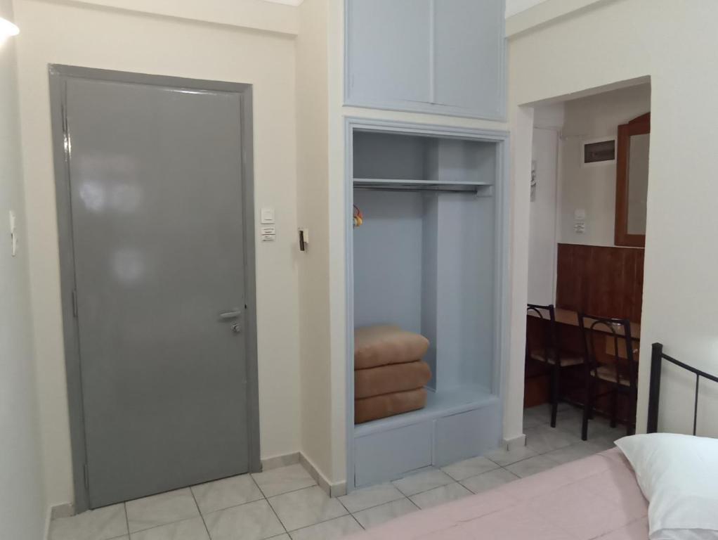 Gaiša istaba ar pelēkām durvīm, iebūvētu skapīti un koka galdu ar krēsliem. Telpā ir gulta ar spilvenu.
