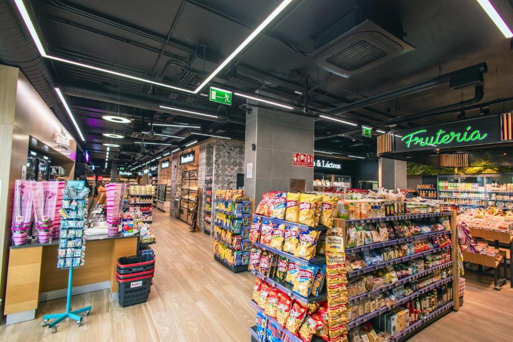 Mūsdienīgs veikals ar plašu produktu klāstu, iekļaujot čipsus un augļus. Apgaismojums uzsver modernu interjeru un kārtību.