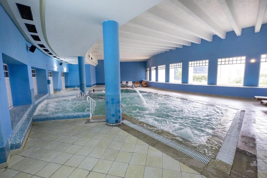 Iekštelpu peldbaseins ar burbuļvannu un gaiši zilu interjeru, kas nodrošina relaksējošu atmosfēru. Plašas logu ailes ļauj ienākt dabiskai gaismai.