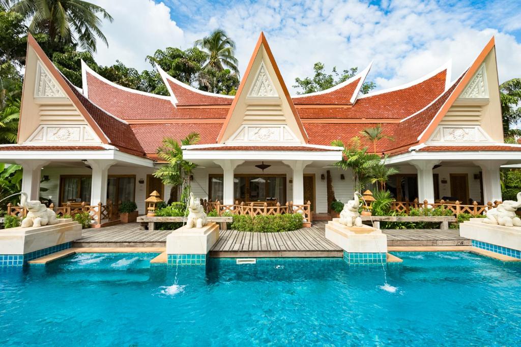 Tropu villa ar stilizētu jumtu un baseinu, ieskauta zaļām palmām un dārziem. Ideāls atpūtas galamērķis siltās klimatiskajās zonas.