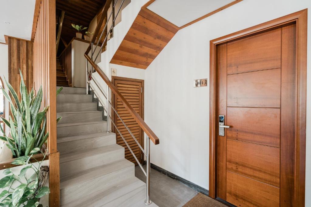 Mūsdienīgs interjers ar koka kāpnēm un ieeju, kurā redzama brīnišķīga augu kompozīcija. Dekorēts ar dabīgiem materiāliem un siltām krāsām.