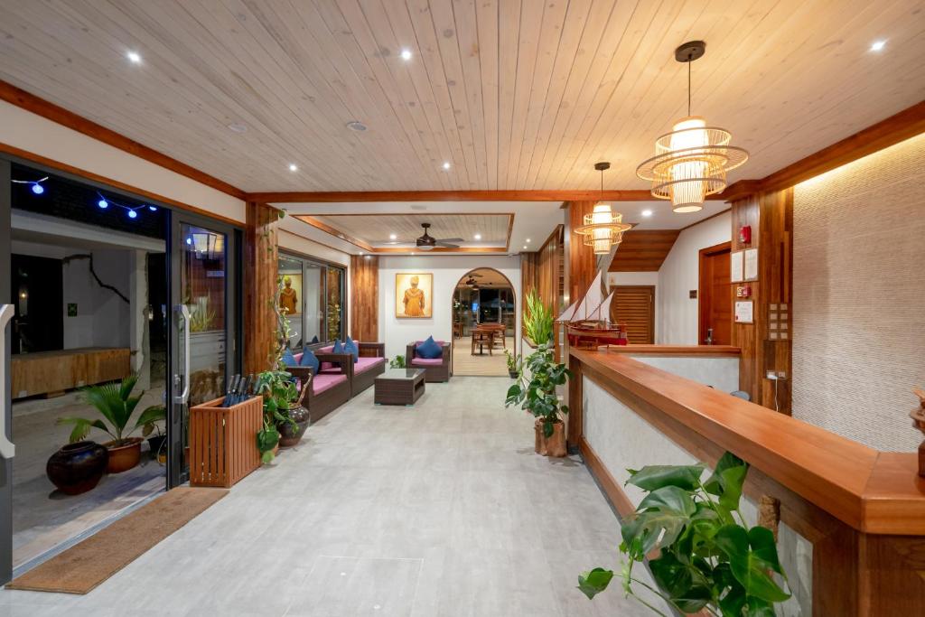 Mūsdienīgs viesnīcas vestibils ar koka griestiem, elegantiem apgaismojuma elementiem un augu dekorācijām. Telpā ir atpūtas zonas ar dīvāniem un centrālā daļa ar reģistratūru.