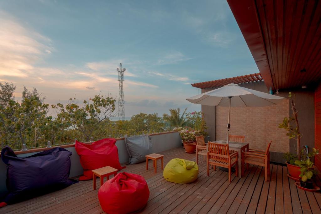 Terase ar krēsliem un dīvāniem, kas apkārt ir zaļumi un puķes, un skats uz debesīm ar mākonīšiem. Tuvumā redzams mobilo sakaru tornis.