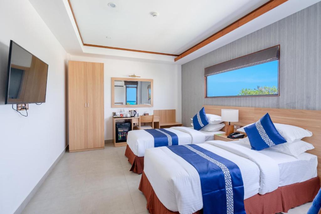 Mūsdienīga viesnīcas istaba ar divām vienguļamām gultām, televizoru un darba stūri. Logā redzams zaļš ainava, piešķirot telpai gaisīgu atmosfēru.