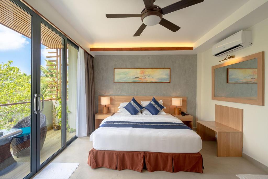 Mūsdienīga guļamistaba ar plašu balkonu un skatu uz dabu, kurā ir ērta gulta, moderns ventilators un elegants dizains. Iekārtojums ietver koka elementus un gaismas avotus, radot patīkamu atmosfēru.