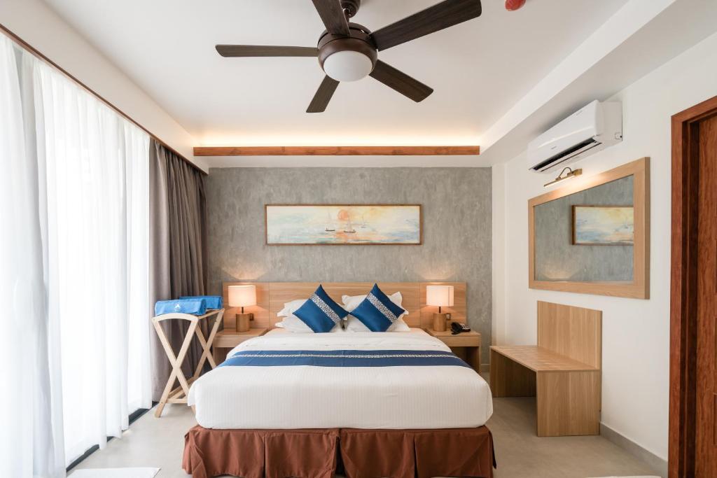 Mūsdienīga viesnīcas numuriņa iekārtojums ar ērtu gultu, dabisku apgaismojumu un stilīgām mēbelēm. Numurā ir ventilators, rakstāmgalds un mākslas darbs uz sienas.