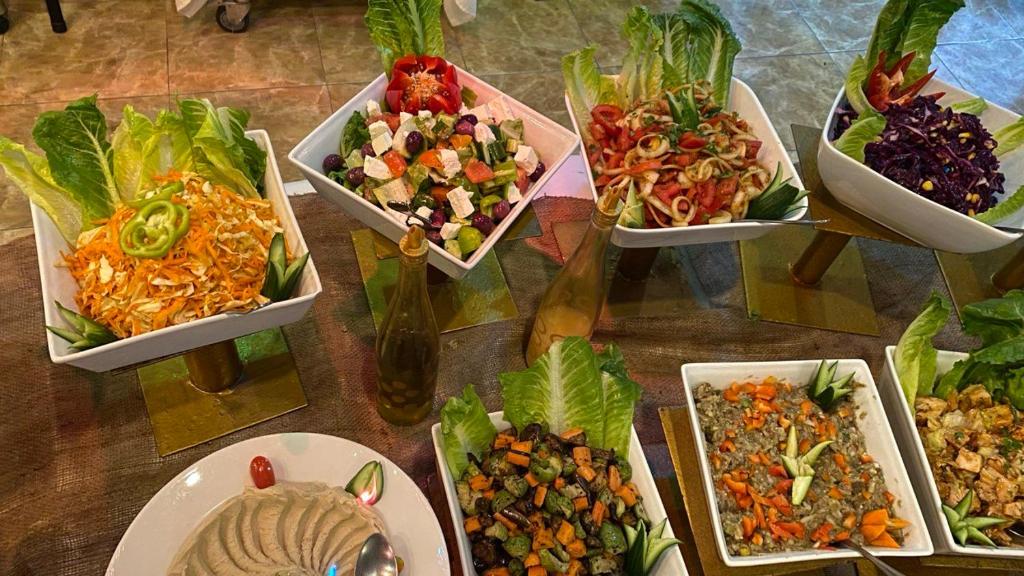 Krāšņs dārzeņu salātu bufete ar dažādām garšīgām salātu bļodām, tostarp burkānu, tomātu un ziedkāpostu salātiem, kas pasniegti ar svaigiem salātiem. Ideāla iespēja veselīgām maltītēm.