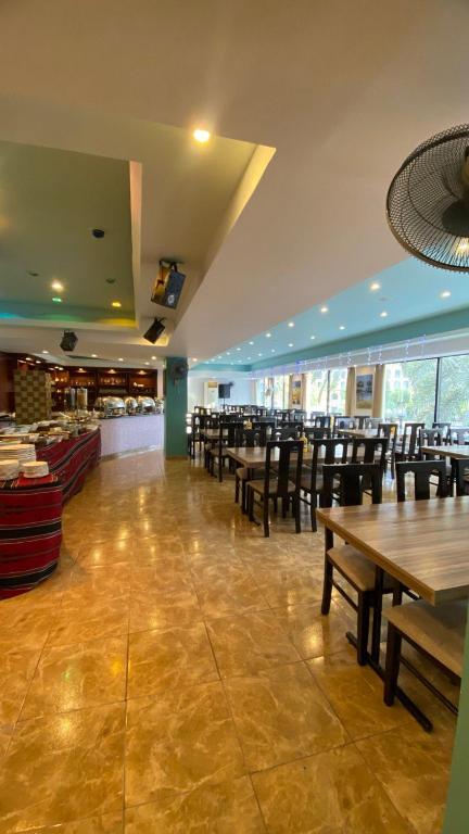 Mūsdienīga restorāna iekārtojums ar plašu telpu, koka galdiem un krēsliem, kas gaida apmeklētājus. Apskatāma bufete un lieli logi, kas nodrošina dabisko apgaismojumu.