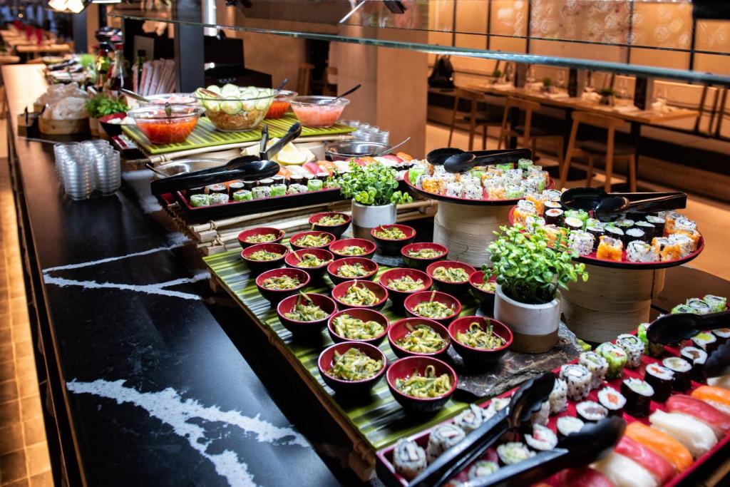 Svaigu suši un salātu bufete ar dažādiem ēdieniem un dekoratīviem elementiem. Ideāls skats uz gardām uzkodām un krāsainām sastāvdaļām.