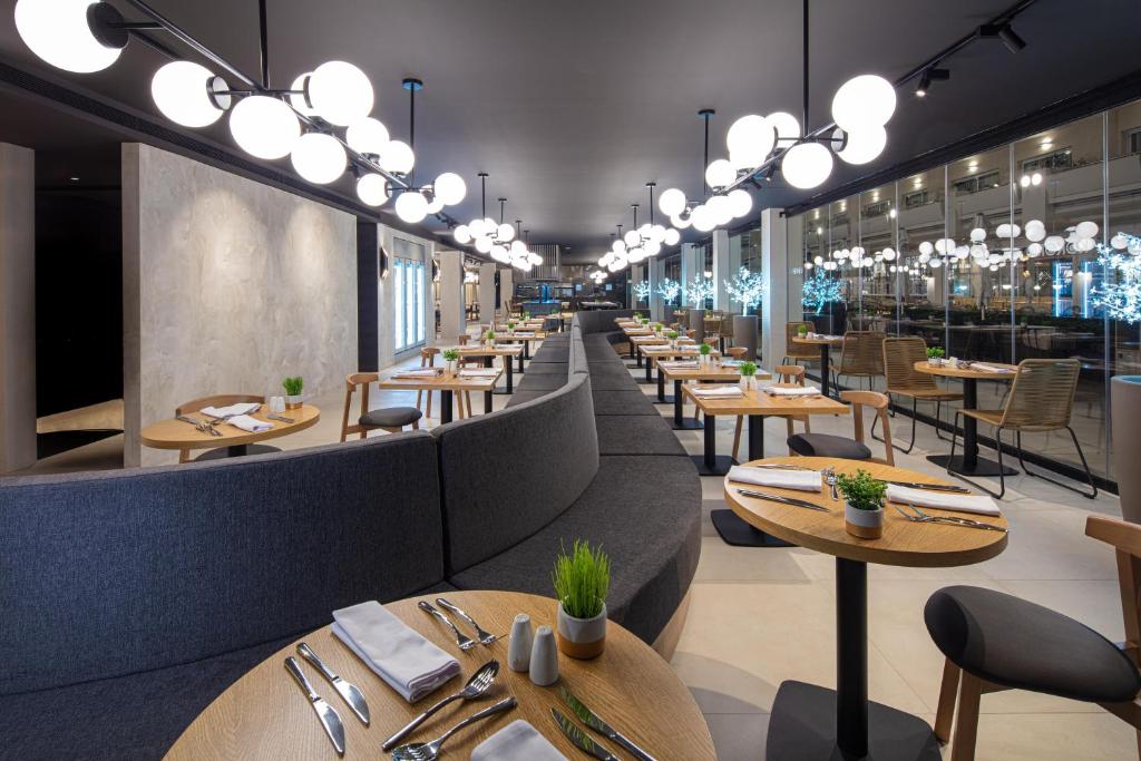 Mūsdienīgs restorāns ar elegantiem galdiem un krēsliem, kas apgaismots ar stilīgām lampām. Interjers ir gaišs un viesmīlīgs, radot patīkamu atmosfēru.