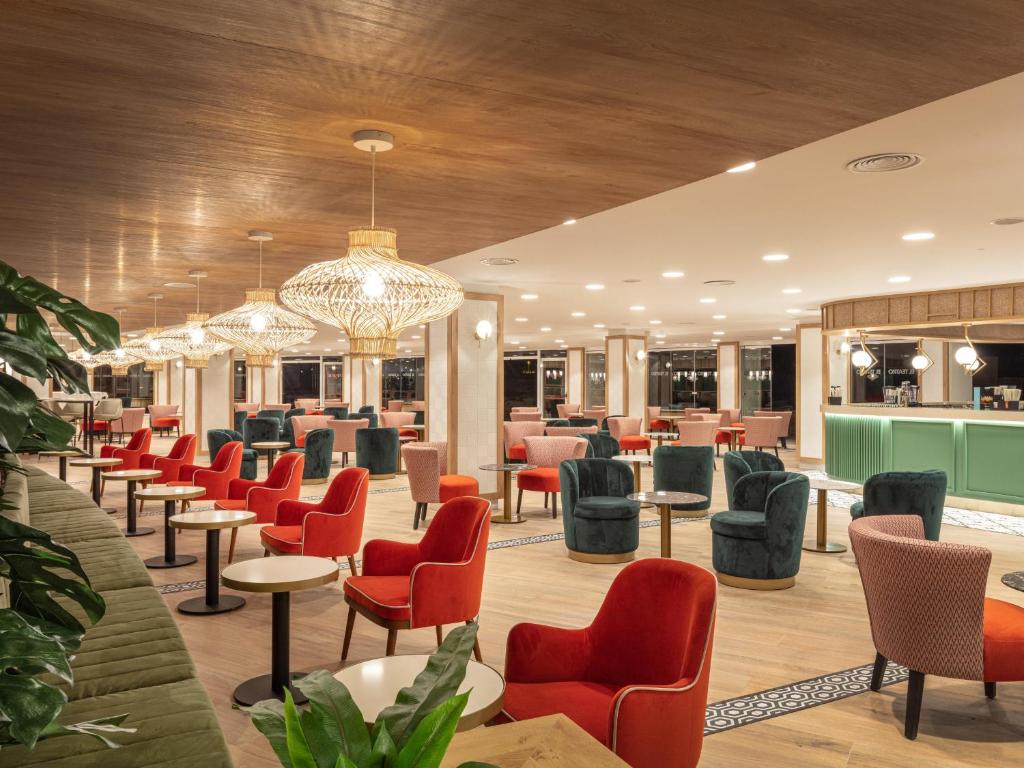 Mūsdienīgs kafejnīcas interjers ar spilgtām krēsla krāsām, siltu apgaismojumu un elegantu dizainu, radot patīkamu atmosfēru. Ideāla vieta relaksācijai un socializācijai.