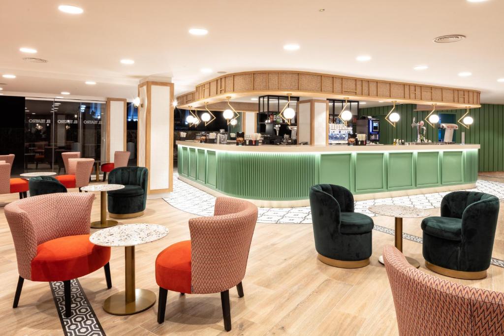 Mūsdienīgs bārs ar elegantiem krēsliem un galdiem, kas veidots ar zaļām un sarkankrāsām akcentiem. Apgaismojums rada patīkamu atmosfēru, ideāli piemērots relaksācijai un socializēšanai.