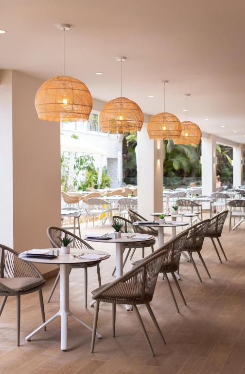 Mūsdienīgs restorāna interjers ar vītņu lampām un elegantām krēslām, radot patīkamu atmosfēru. Gaismas un telpas dizains veicina relaksāciju un baudījumu.