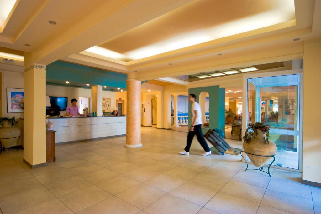 Labi iekārtota viesnīcas recepcija ar elegantu interjeru, kur viesis ienāk ar bagāžu. Gaisma ir silta un telpa ir plaša un viesmīlīga.
