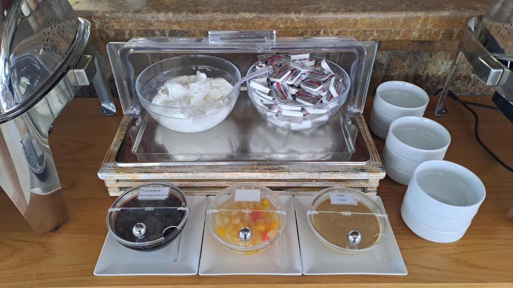 Brokastu bufete ar dažādām piedevām, tostarp krējumu, saldinātājiem un augļu sīrupiem. Izvēle ietver šokolādes mērci un dažādus saldumus.