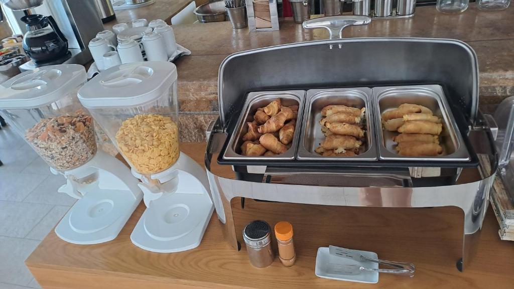 Brokastu bufete ar dažādām graudaugu un uzkodu izvēlēm, tostarp ceptiem produktiem un riekstu maisījumiem. Ideāla vieta, lai sāktu dienu ar garšīgām maltītēm.