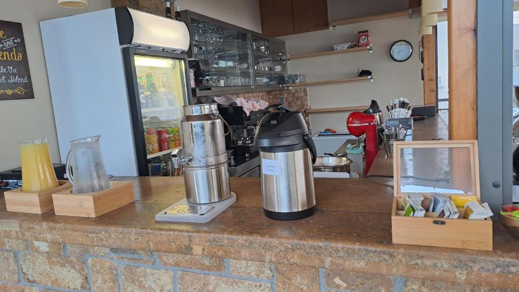 Kafejnīcas bārs ar dzērieniem, tējām un kafijas aparātu, kā arī ledusskapis ar uzkodām. Dekorēts ar koka elementiem un plauktiem.